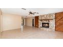 Spacious living room featuring a stone fireplace, ceiling fan, and tile flooring, perfect for relaxation and entertaining at 2485 Se 159Th Lane Rd, Summerfield, FL 34491