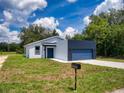 Charming single-story home with blue garage door, front yard, and well-maintained landscaping at 28 Guava Ln, Ocklawaha, FL 32179