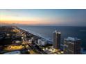 Aerial view of beachfront condos and city skyline at twilight, highlighting coastal living at 3000 N Atlantic Ave # 24, Daytona Beach, FL 32118