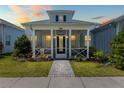 Charming light blue single-story home featuring a cozy front porch and meticulously landscaped yard at dusk at 562 Landshark Blvd, Daytona Beach, FL 32124