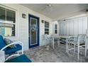 Inviting outdoor patio featuring brick flooring, a ceiling fan, comfortable seating and a decorated front door at 562 Landshark Blvd, Daytona Beach, FL 32124