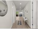 Bright hallway with white walls, wood floors, a console table and a peek into the modern kitchen at 72 Aurora Ave, Ponce Inlet, FL 32127