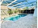 Relax by the private screened-in pool featuring brick pavers, lush landscaping, and a serene waterfall at 112 Muscovy Ct, Daytona Beach, FL 32119