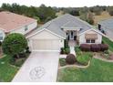 Aerial view of a single Gathering home featuring an attached two car garage and manicured lawn at 12841 Se 97Th Terrace Rd, Summerfield, FL 34491