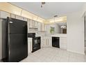 Well-lit kitchen featuring black appliances, tile flooring, and ample cabinet space at 160 Limewood Pl # 1, Ormond Beach, FL 32174