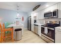 Modern kitchen featuring white cabinets, stainless steel appliances, and a breakfast bar area with colorful stools at 3700 S Atlantic Ave # 111, New Smyrna Beach, FL 32169