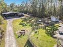 Aerial view of the property showcasing the garage, play set, firepit, shed, and surrounding landscape at 4252 Quail Ranch Rd, New Smyrna Beach, FL 32168