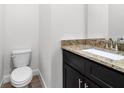 Stylish half bath with granite countertop, dark wood vanity and tiled floor at 559 Coronado Cove Rd, New Smyrna Beach, FL 32168