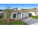 Attractive single-story home featuring a stone facade, gray exterior, paver driveway, and well-manicured lawn at 875 Honey Petal Ln, Deland, FL 32720