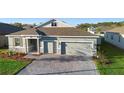 Beautiful single-story home with a gray exterior, brick driveway, well-maintained lawn, and inviting curb appeal at 875 Honey Petal Ln, Deland, FL 32720