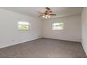 Bright bedroom with neutral carpet, ceiling fan, and natural light from two windows at 953 Pineapple Rd, South Daytona, FL 32119