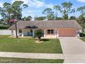 Charming single-story home with a manicured lawn, palm tree, sidewalk and two-car garage at 1489 Casey Ln, Port Orange, FL 32129