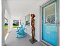 Inviting front porch with rocking chairs, a unique wooden sculpture, and a turquoise front door at 1489 Casey Ln, Port Orange, FL 32129