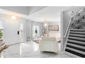 Elegant foyer featuring a staircase, a modern light fixture, and sleek marble floors leading to a bright living space at 3318 Dewberry Dr, Deltona, FL 32738