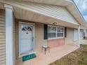 Inviting front porch with tan siding and a white front door with window and 'hello' doormat at 412 Cherry St, South Daytona, FL 32119