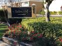 Ashwood Condominiums sign with flowers and greenery surrounding it at 1000 Lake Of The Woods Blvd # 104F, Casselberry, FL 32730