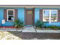Inviting front entry featuring a brown front door, garden beds, stone accents and lush landscaping at 3057 Norlina St, Deltona, FL 32738