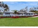 A charming one-story home features black shutters, green grass and a walkway to the front door at 7108 East Rd, Lakeland, FL 33809