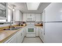 Bright kitchen with white cabinetry, appliances, light countertops, and vinyl flooring at 935 Ocean Shore Blvd # 4010, Ormond Beach, FL 32176
