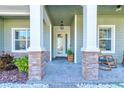 Inviting covered front porch with stone columns, rocking chairs, and decorative lighting at 1204 Draycott St, Ormond Beach, FL 32174