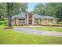 Lovely single-story brick home featuring a circular driveway and lush landscaping at 1500 Wyngate Dr, Deland, FL 32724