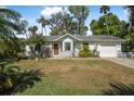 Single-story home boasts a tidy front lawn, mature trees, and attached garage at 2249 Swoope Dr, New Smyrna Beach, FL 32168