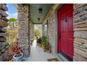 Inviting front porch with stone columns and a vibrant red door at 3894 Arborvitae Way, Deland, FL 32724