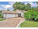 Attractive single-story home with a tile roof, brick driveway, and mature landscaping at 509 Osprey Ln, Winter Springs, FL 32708