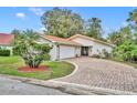 A single-story home with a tile roof, brick driveway, attached garage, and charming landscaping at 509 Osprey Ln, Winter Springs, FL 32708