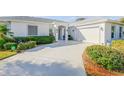 Close up of home with manicured shrubs, a winding driveway, a two-car garage, and double door entry at 65 Calumet Ave, Ponce Inlet, FL 32127