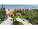 Beautiful home with terracotta roof tiles and a circular driveway, showcasing the lush landscaping at 201 Ocean Shore Blvd, Ormond Beach, FL 32176