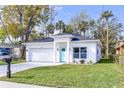 Charming single-story home with a white exterior, attached garage, and well-manicured front yard at 414 Ellsworth St, Daytona Beach, FL 32114