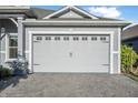 Close-up of the attached two-car garage featuring decorative windows and a paved driveway at 6263 W Fallsgrove Ln, Port Orange, FL 32128