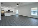 Open concept living space with gray flooring, large windows, and a ceiling fan, adjacent to the kitchen at 951 Redwood St, Daytona Beach, FL 32117