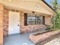 Charming brick home exterior featuring a front porch with brick planter, white door, and window with shutters at 1002 Charles St, Port Orange, FL 32129