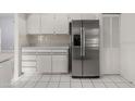 Bright kitchen featuring stainless steel refrigerator, white cabinets, and tile flooring at 102 Underbrush Trl, Port Orange, FL 32128