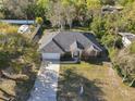 Aerial view of a single-story brick home with a gray roof, an attached garage, and a long driveway at 151 Lucerne Dr, Debary, FL 32713