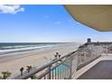 Balcony view of the beach, ocean, palm trees, and community pool below at 1900 N Atlantic Ave # 504, Daytona Beach, FL 32118