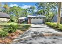 Quaint one-story home with a wide driveway, a two-car garage, and a well-maintained lawn with mature trees at 29 Ramblewood Trl, Deland, FL 32724