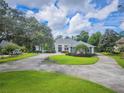 Landscaped front yard featuring a circular driveway leading to a well-maintained one story home with mature trees at 369 Caddie Dr, Debary, FL 32713