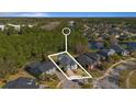 Aerial view of a beautiful blue home with lush green trees surrounding it in a serene neighborhood near a lake at 376 Chelsea Place Ave, Ormond Beach, FL 32174