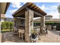Outdoor kitchen with brick pillars, built in seating, and a full bar at 3955 Equine Cv, Lake Mary, FL 32746