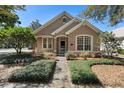 Charming tan home featuring a manicured front yard with beautiful landscaping and a pathway to the front door at 406 Ravenshill Way, Deland, FL 32724
