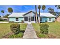 Inviting single-story home with a screened-in porch, manicured lawn, and a charming sidewalk entrance at 437 Merrimac Dr, Port Orange, FL 32127