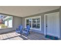 Inviting covered porch featuring wood-look floors, natural light, and two comfortable blue chairs at 437 Merrimac Dr, Port Orange, FL 32127
