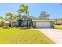 Beautiful single-story home with lush green lawn, palm trees, and a brick-paved driveway leading to a two-car garage at 6 Greenvale Dr, Ormond Beach, FL 32174