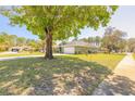 Attractive green home with lush landscaping and a long brick-paved driveway leading to a two-car garage, shaded by mature trees at 6 Greenvale Dr, Ormond Beach, FL 32174