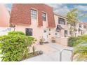 Inviting pink townhome with a red roof and black-trimmed windows complemented by lush green shrubs at 108 Mitchell Pl # 108, Daytona Beach, FL 32118