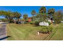 Indigo Woods Condominium community sign surrounded by lush landscaping and mature palm trees at 112 Lacosta Ln # 115, Daytona Beach, FL 32114