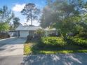Exterior view of home showcasing metal roof, stone accents, lush landscaping and large shade trees at 3228 Unity Tree Dr, Edgewater, FL 32141